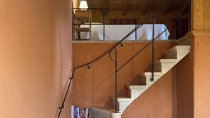 A staircase with a metal railing leading to an upper level, a dining table with a vase and books, and a chair. - A 75 m² self-contained vacation rental surrounded by nature, fully equipped with all modern comforts, for 2 people (Saou)