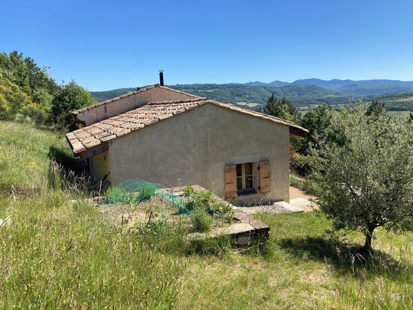 A rustic house with a tiled roof, a chimney, and a small window.