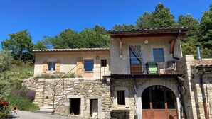 A rustic stone building with a balcony, a wooden door, and a small window. - A 75 m² self-contained vacation rental surrounded by nature, fully equipped with all modern comforts, for 2 people (Saou)