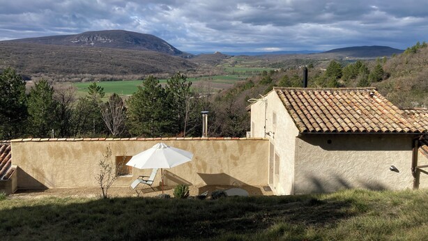 A rustic building with a tiled roof, a white umbrella, and a view of rolling hills and a mountain in the distance. - A 75 m² self-contained vacation rental surrounded by nature, fully equipped with all modern comforts, for 2 people (Saou)