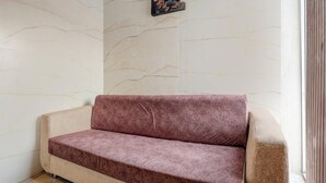 Een beige bank met een bruin kussen in een kamer met marmeren wanden en een foto op de muur.