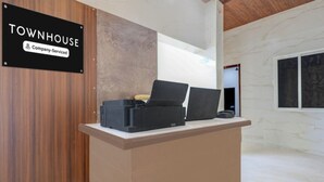 Een receptiebalie met een bord waarop 'TOWNHOUSE Company-Serviced' staat, en een houten wand op de achtergrond.