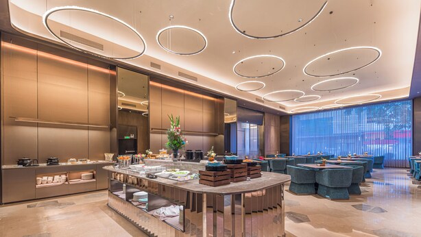 A modern hotel lobby with a central island, seating areas, and a large window. - Orange Crystal Hotel Yangjiang (Yangjiang)