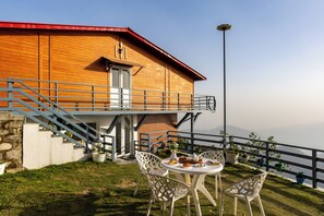 Ein Holzgebäude mit Balkon, Sitzgelegenheiten im Freien und Pflanzkübeln.