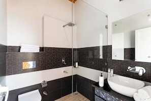 A modern bathroom with a glass-enclosed shower, a white sink, and a marble countertop.