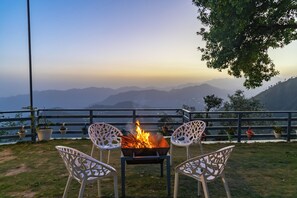 A fire pit with chairs, a railing, and a view of distant mountains.