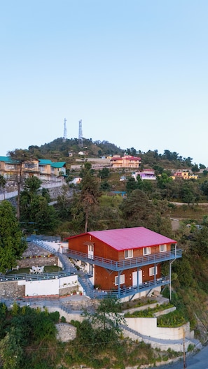 A multi-story building with a red roof, a balcony, and a staircase leading to the upper floor.
