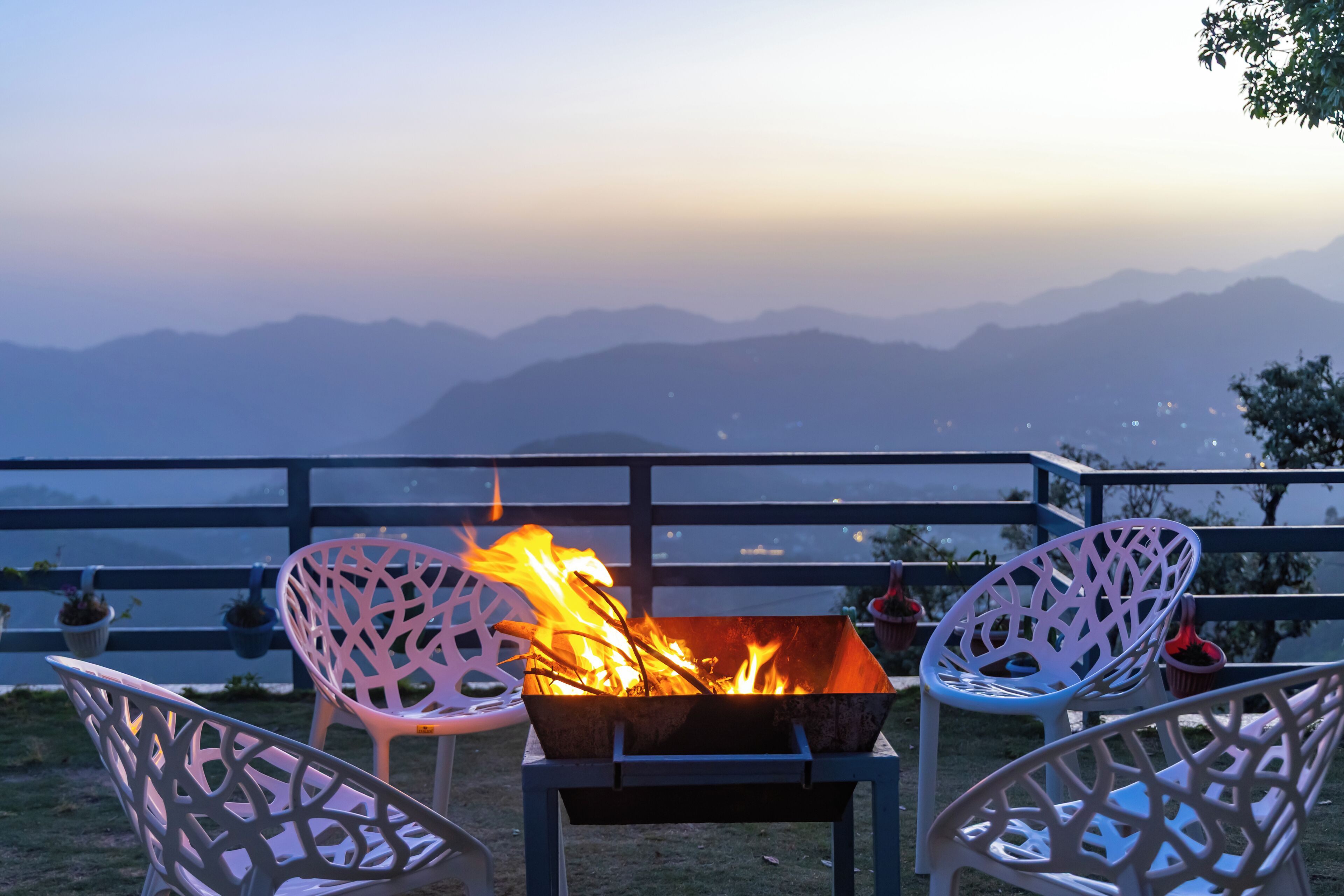 A fire pit with chairs, a railing, and a mountainous backdrop.