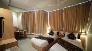 Quarto de hotel com duas camas, uma escrivaninha e uma cadeira.