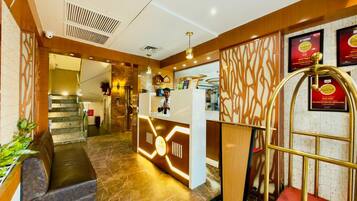 Vestíbulo de hotel con una recepción, una escalera y un área de descanso.