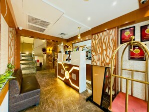 A hotel lobby with a reception desk, a staircase, and a seating area. - Hotel Vagmi (Varanasi)
