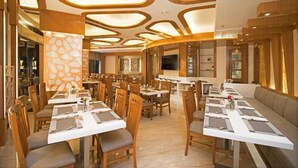 Um restaurante com várias mesas de jantar, cadeiras de madeira e um design de teto moderno.
