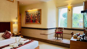 A hotel room with a bed, a chair, a desk, a painting, and a window.