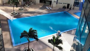 Una piscina circondata da palme e un edificio a più piani con balconi.