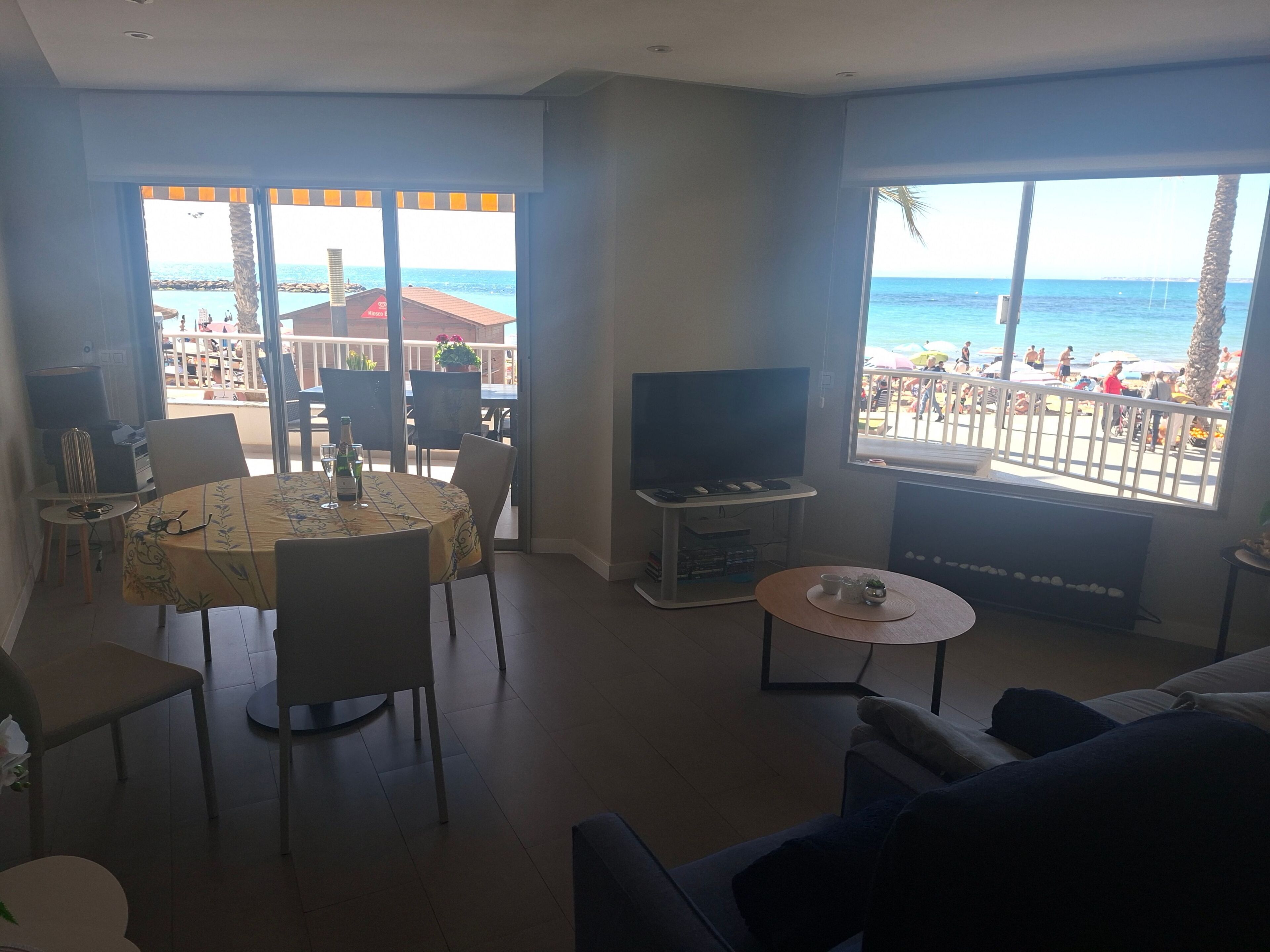 Un salon avec un téléviseur, une table à manger et une vue sur la plage.