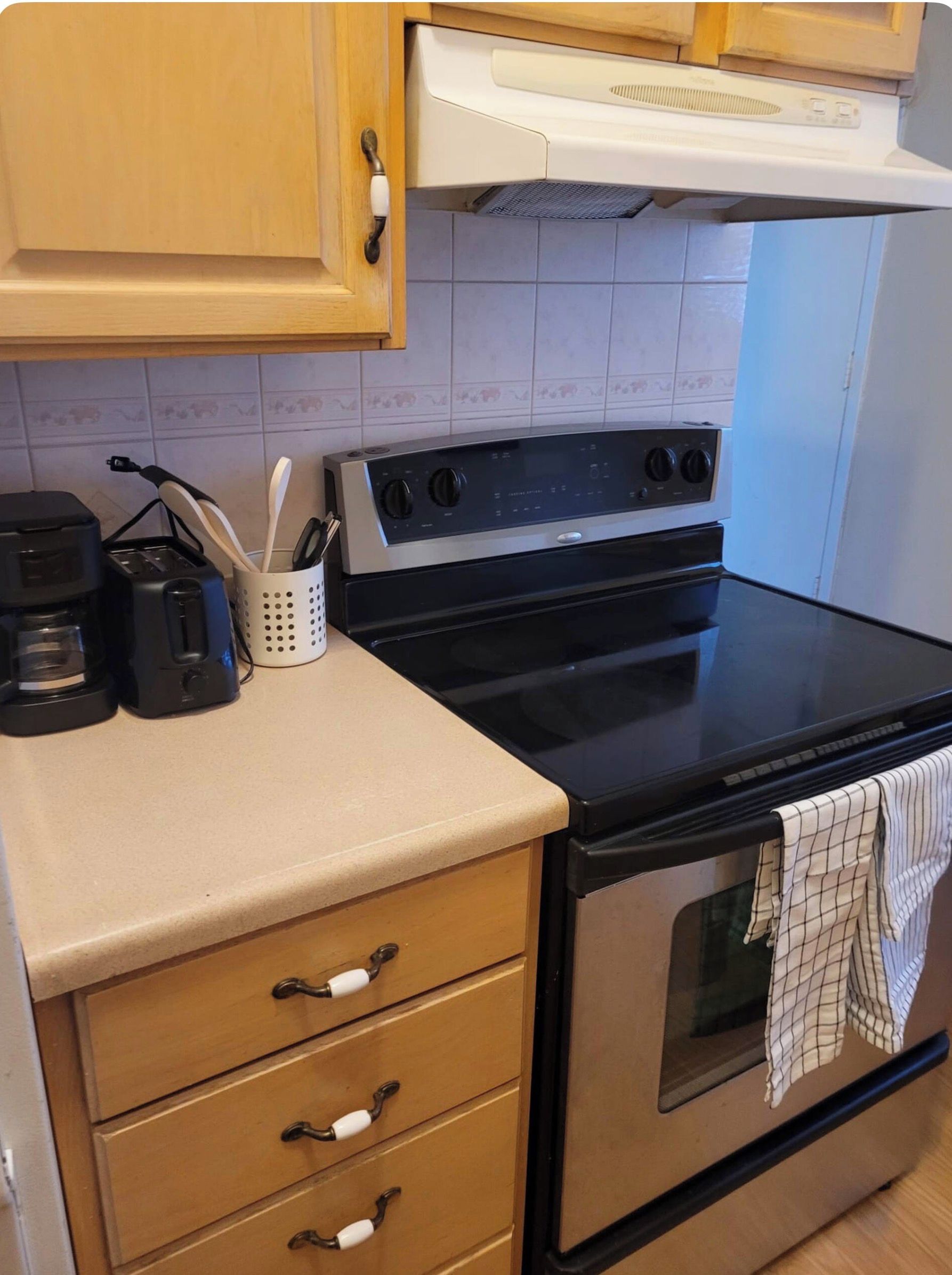 A kitchen with a stove, oven, and a coffee maker on the countertop.