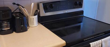 A kitchen with a stove, oven, and a coffee maker on the countertop.