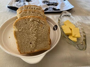 A plate with slices of bread and a glass dish with butter.