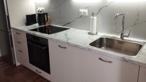 A modern kitchen with a built-in stove, a sink, and a coffee maker. - Seizani Athens Stay-1,6 km from Panathenaic Stadium (Kaisariani)