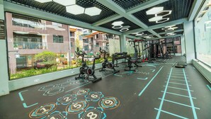 Un gimnasio con equipo de ejercicio, un diseño de suelo hexagonal y amplias ventanas con vistas a una zona residencial.