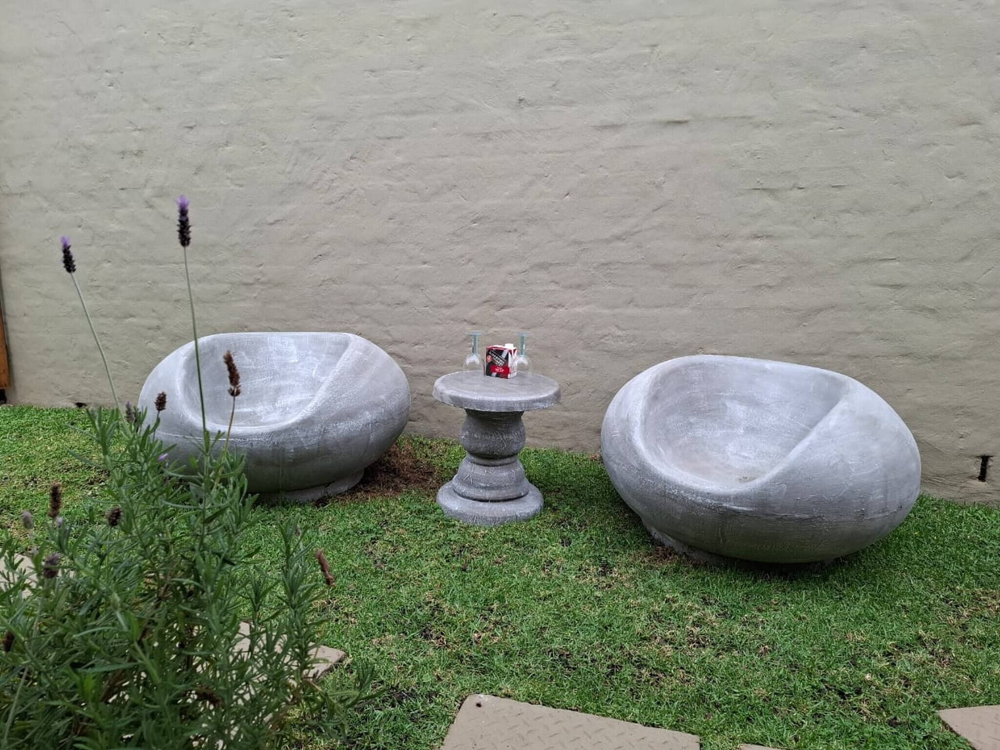 A garden with two stone planters and a small table with a bottle.