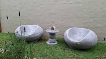 A garden with two stone planters and a small table with a bottle.