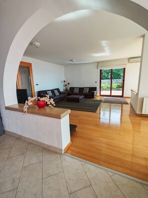 Un espacio habitable abierto con un conjunto de sofás, una mesa de centro de madera y un jarrón decorativo con flores.