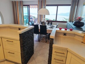 A modern kitchen with stone accents, a dining area with a view, and a large window. - Villa Vrata Jadrana 1 (Rijeka)