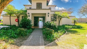 A two-story house with a paved entrance, surrounded by lush greenery and a clear sky. - 3 bed Cluster home in Sandton (Sandton)