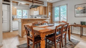 Una cucina con armadietti in legno, un tavolo da pranzo con sedie, un lampadario e un quadro appeso al muro.