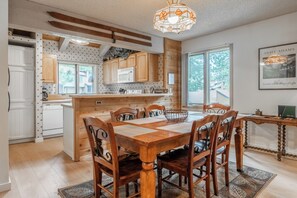 A kitchen with wooden cabinets, a dining table with chairs, a chandelier, and a framed picture on the wall. - Wildflower 60: Nice, Centrally Located (Mammoth Lakes)