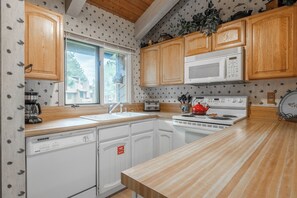 A kitchen with wooden cabinets, a microwave, a stove, and a dishwasher. - Wildflower 60: Nice, Centrally Located (Mammoth Lakes)