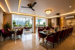 Une salle à manger spacieuse avec un plafond haut, un lustre moderne et un ventilateur de plafond.