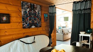 A wooden cabin interior with a sofa, a dining table with a fruit bowl, and a painting on the wall. - Le Chalet Sablais 150m from the beach (Les Sables-d´Olonne)