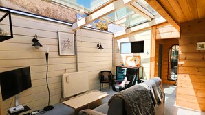 A cozy room with a sofa, a table, a chair, a TV, and a skylight. - Le Chalet Sablais 150m from the beach (Les Sables-d´Olonne)