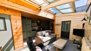A modern interior with a sofa, a coffee table, and a TV. - Le Chalet Sablais 150m from the beach (Les Sables-d´Olonne)