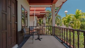 A balcony with a table and chairs, a wooden door, and a view of palm trees. - 1 Bedroom with living room and kittchenette 700meters to Rawai beach (Phuket)
