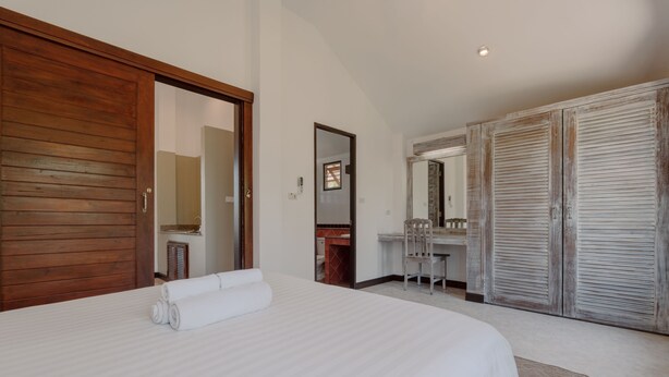 A hotel room with a large bed, a wooden wardrobe, a mirror, and a desk with a chair. - 1 Bedroom with living room and kittchenette 700meters to Rawai beach (Phuket)
