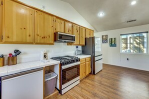 A kitchen with wooden cabinets, a microwave, stove, refrigerator, and a window with a view. - Big Bear Nature Escape! Cabin 7 Mi to Lake (Big Bear)