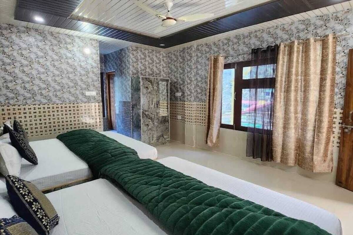 A bedroom with a large bed, a smaller bed, a ceiling fan, and patterned wallpaper.