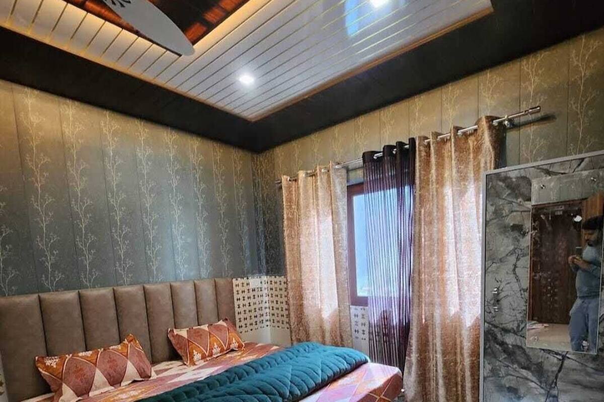 A bedroom with a large bed, a ceiling fan, and a view of a bathroom.