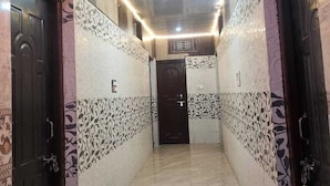 Um corredor com paredes padronizadas, chão de azulejos e portas em ambos os lados.