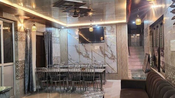 Um quarto amplo com uma mesa de jantar comprida, cadeiras, um sofá e luminárias pendentes.