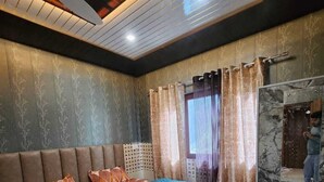 Quarto com cama, cortinas, painel de cabeceira e ventilador de teto.
