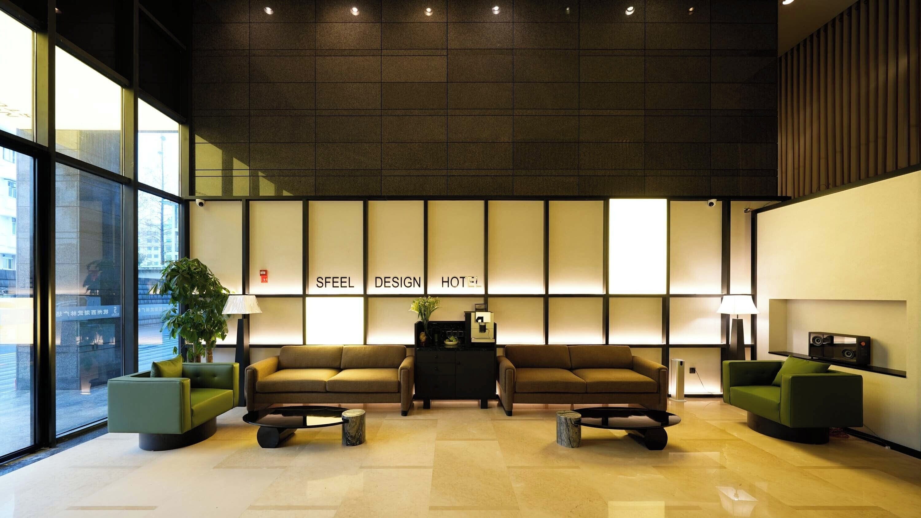 A modern hotel lobby with two sofas, a small table, and a potted plant.