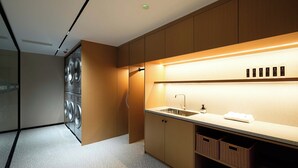 A modern kitchen with a built-in washer and dryer, a countertop sink, and wooden cabinets. - SFEEL Design Hotel Hangzhou Xihu (Hangzhou)