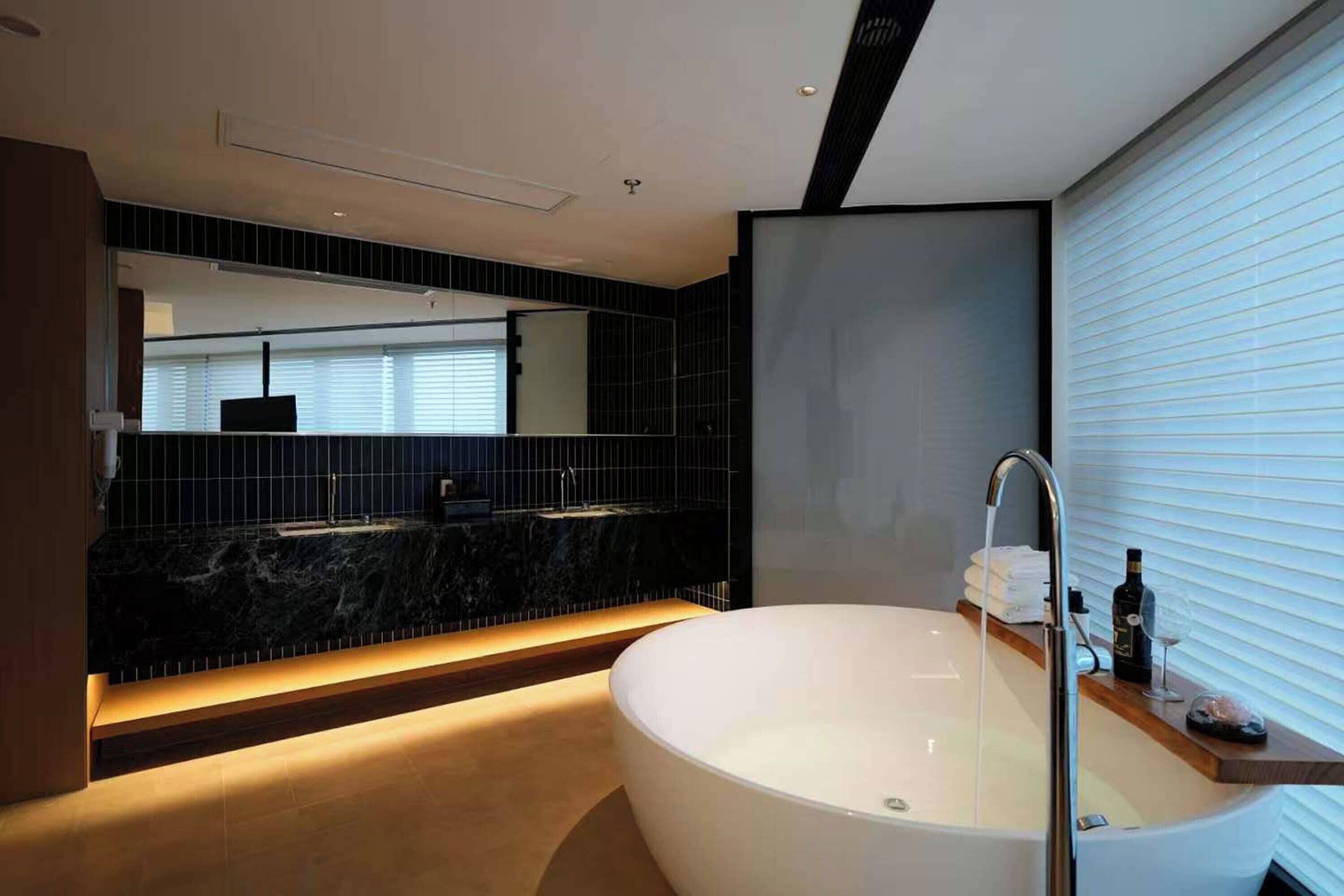 Un baño moderno con una bañera independiente, un espejo grande y un lavamanos en la encimera.