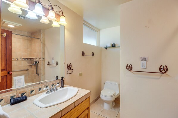 Een badkamer met wastafel, spiegel, handdoekrek en toilet.