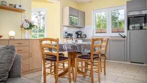 A modern kitchen with wooden chairs, a dining table, and a refrigerator. - Comfortable vacation home Am Deich House 16 with garden and terrace in Zingst - Am (Zingst)