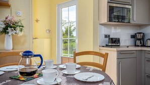 A dining area with a table set for four, a coffee maker, and a view of the outdoors. - Comfortable vacation home Am Deich House 16 with garden and terrace in Zingst - Am (Zingst)